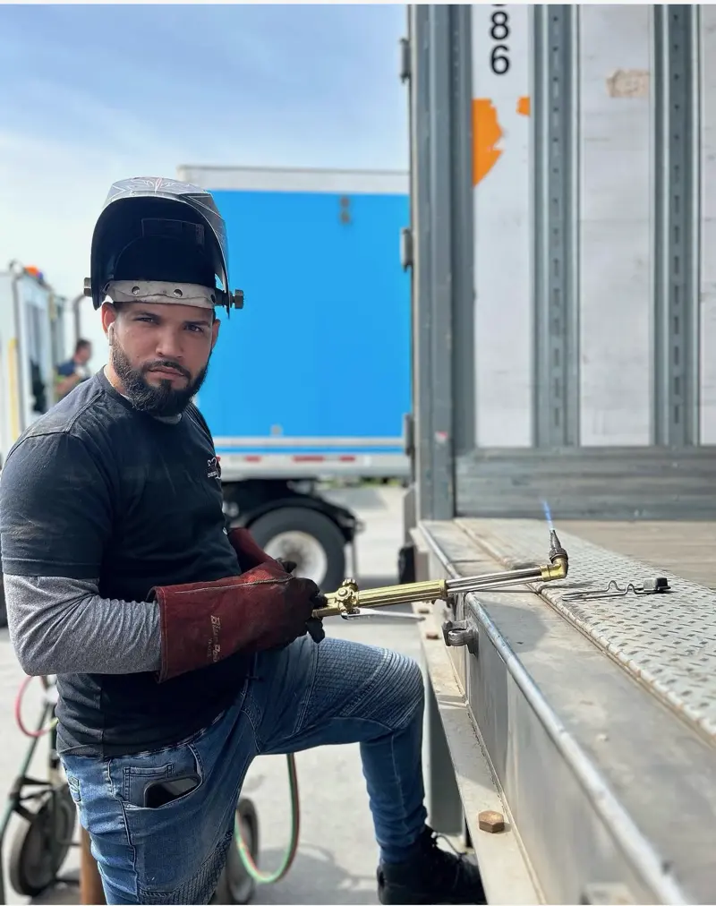 Welder with torch repairing a trailer deck